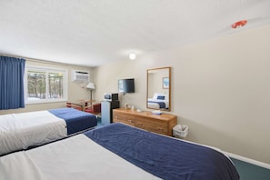 A hotel room with two beds, a desk, a television, a dresser, and a window with curtains. - Eastern Inn Table Mountain Suite (North Conway)