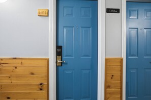 Eine blaue Tür mit einem Schild ‚Nichtraucher‘, ein hölzerner Türrahmen und ein Schild mit der Nummer 121 an der Wand.