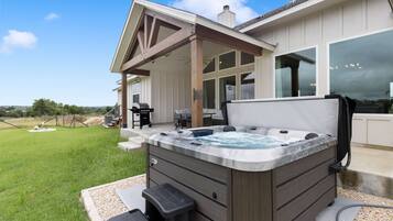 Un bain à remous avec un revêtement extérieur en bois, un patio couvert et une vue sur le paysage environnant.