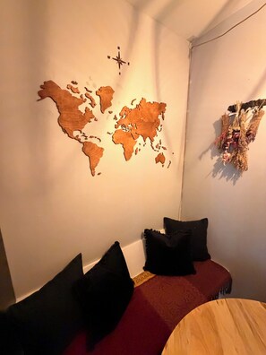 Een kamer met een wereldkaart aan de wand, een houten bed en een klein rond tafeltje.