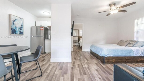 Un espacio habitable compacto con comedor, kitchenette y un dormitorio con cama y ventilador de techo.
