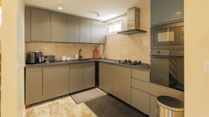 A compact kitchen with grey cabinets, a gas stove, a microwave, and a stainless steel oven.