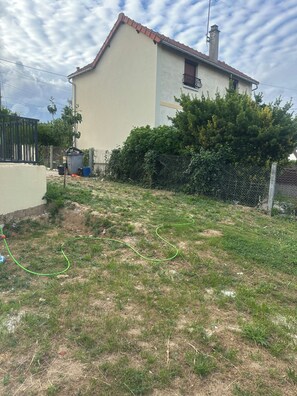 A residential area with a house, a fenced yard, and a garden hose.