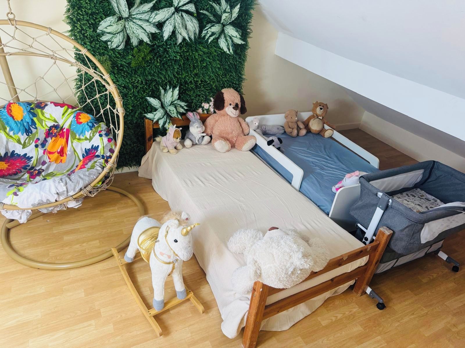 Une chambre d’enfant avec un lit, un fauteuil suspendu et divers jouets en peluche.