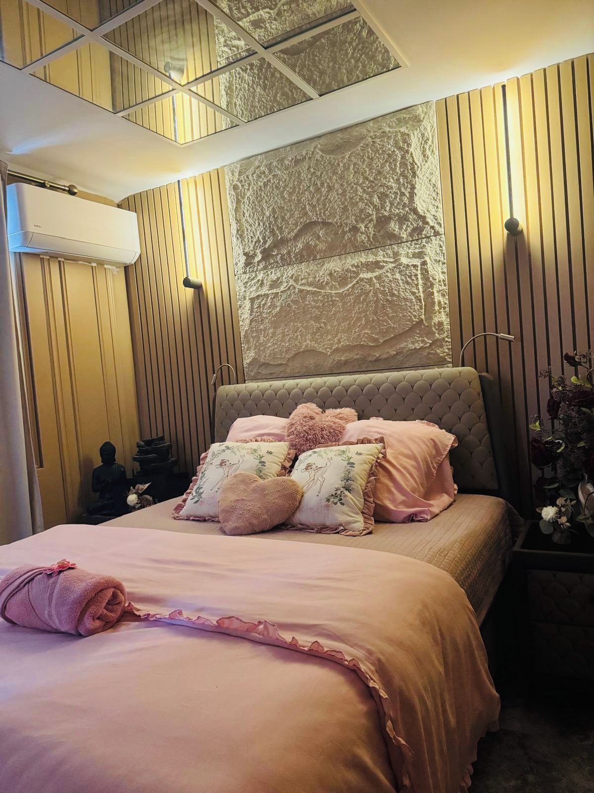 A bedroom with a bed, a wall-mounted air conditioner, and a textured wall design.
