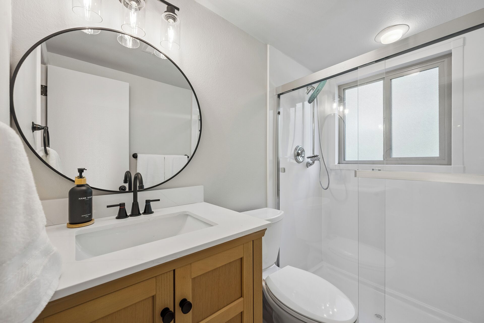 A bathroom with a white sink, a mirror, a toilet, and a shower.