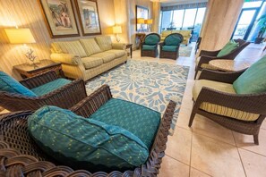 A spacious living area with wicker furniture, a patterned rug, and framed artwork on the walls. - Oceanfront Unit with Private Balcony and Pool Access (Myrtle Beach)