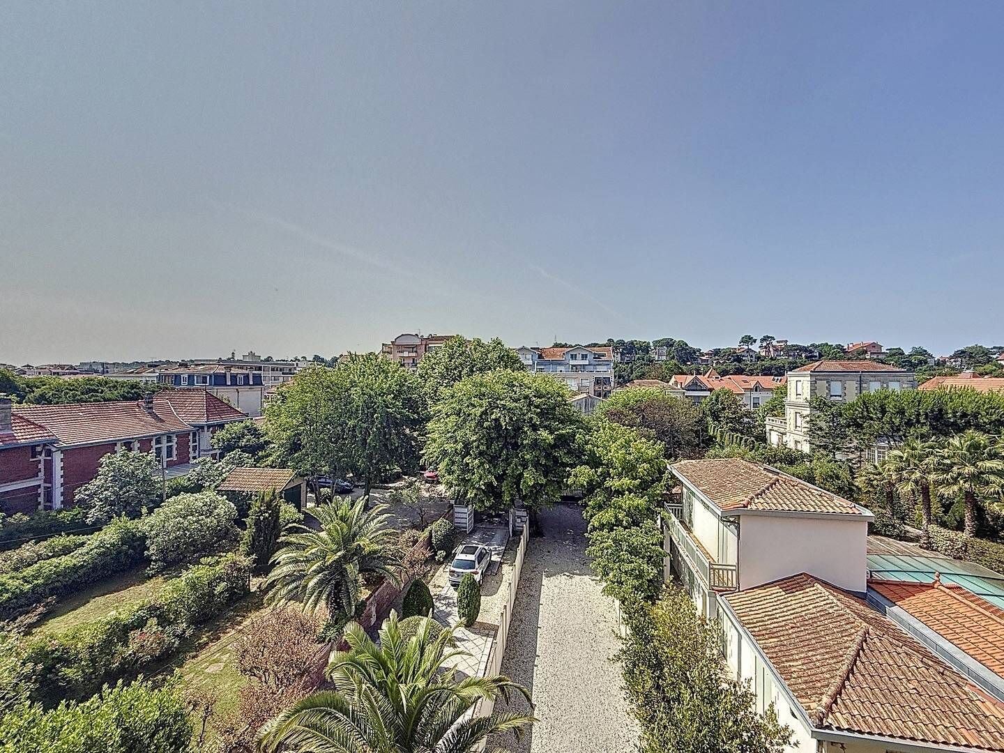 Un quartier résidentiel avec des maisons, des arbres et un ciel dégagé.