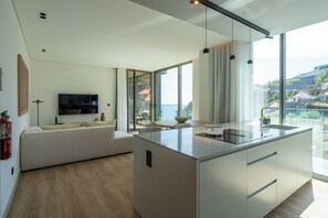 A modern kitchen with a large island, a flat-screen TV, and a view of the city.
