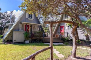A house with a red door, a staircase, and a tree in the foreground.