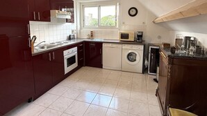 Een kleine keuken met een vaatwasser, oven, magnetron en een raam voor natuurlijk licht.