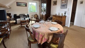 Een eetgedeelte met een ronde tafel gedekt voor vier personen, omringd door houten stoelen.
