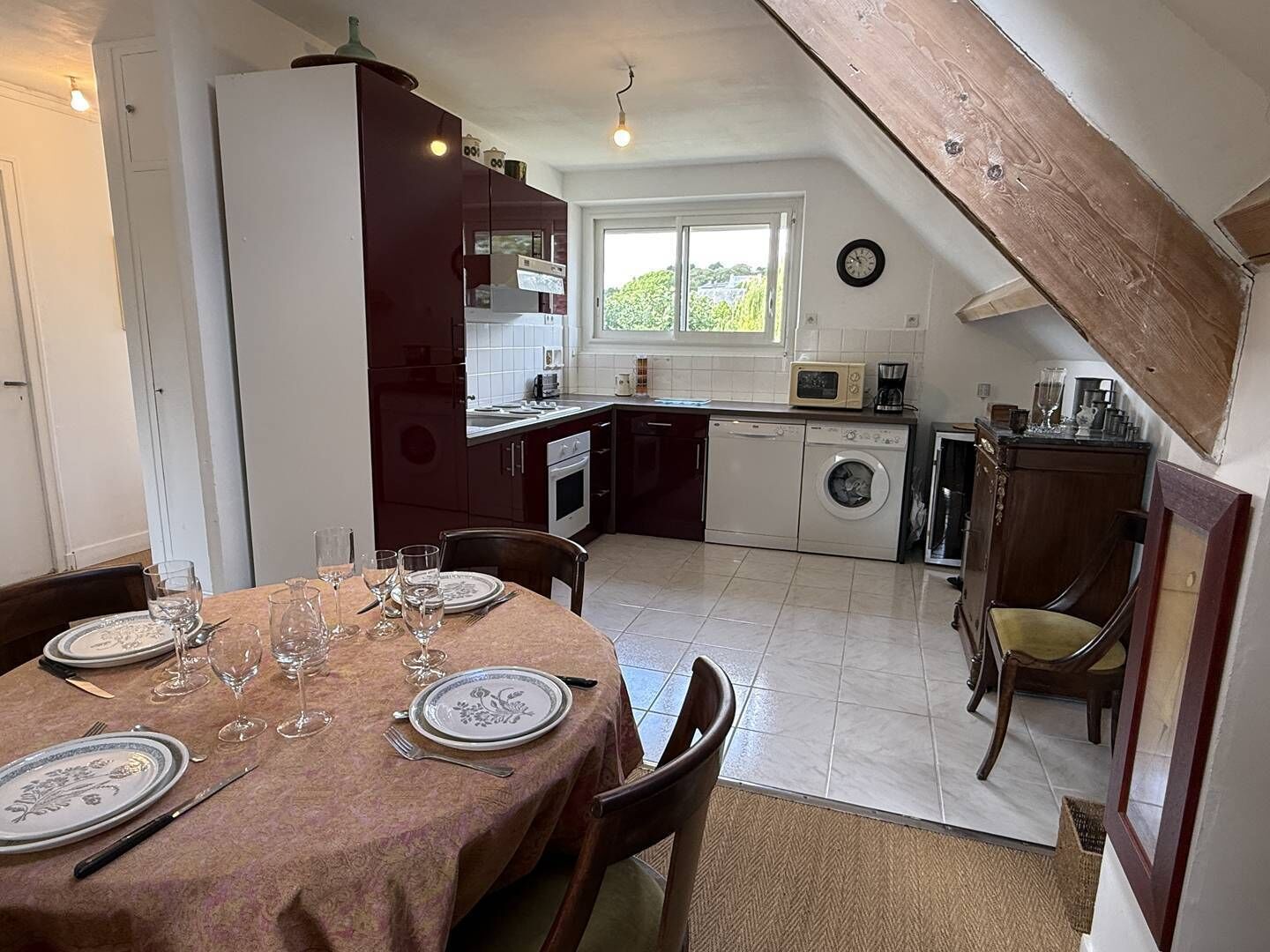 Una cocina con una mesa de comedor para cuatro, una lavadora y un microondas.