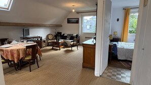 Een knus ingerichte kamer met een eethoek, een bank, een bureau en een bed.