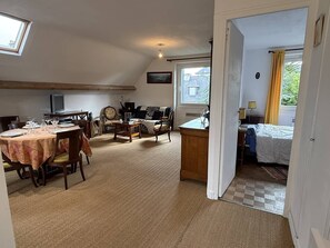 Ein gemütliches Zimmer mit Essbereich, einer Couch, einem Schreibtisch und einem Bett.
