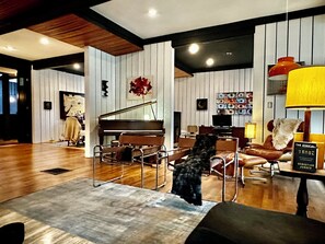 Ein Wohnzimmer mit einem Klavier, einem Hund und einem Bücherregal voller Bücher.