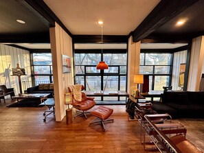 Ein modernes Wohnzimmer mit großem Fenster, einer Ledersofa, einem Couchtisch und Holzboden.
