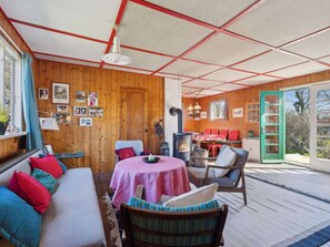 Ein gemütliches Blockhaus mit Holzvertäfelung, einem Essbereich und einem gro ßen Fenster.