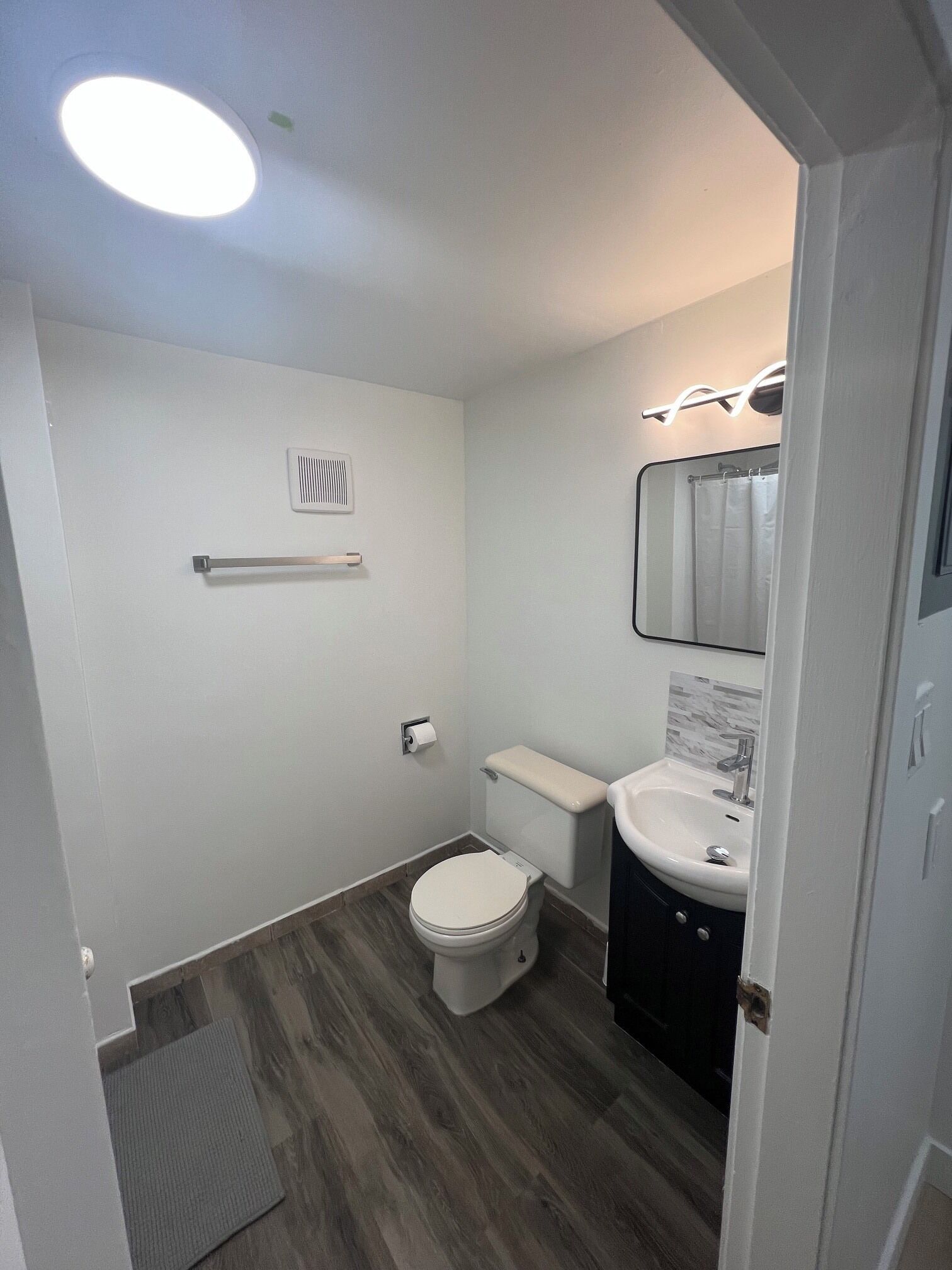 Une petite salle de bain comprenant des toilettes, un lavabo, un miroir et une petite étagère.