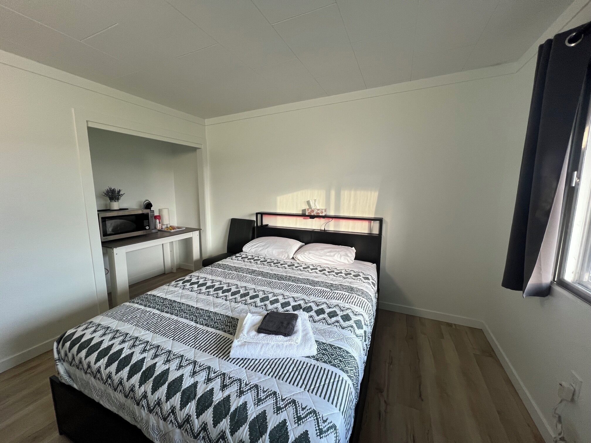 A bedroom with a bed, a desk, and a window.