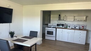 Una cocina moderna con armarios blancos, microondas, estufa y un comedor con mesa y sillas.