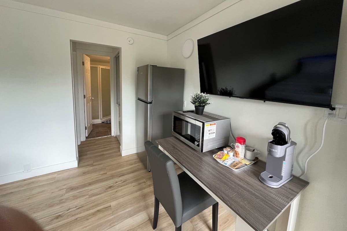 A compact kitchenette with a refrigerator, microwave, coffee maker, and a small potted plant.
