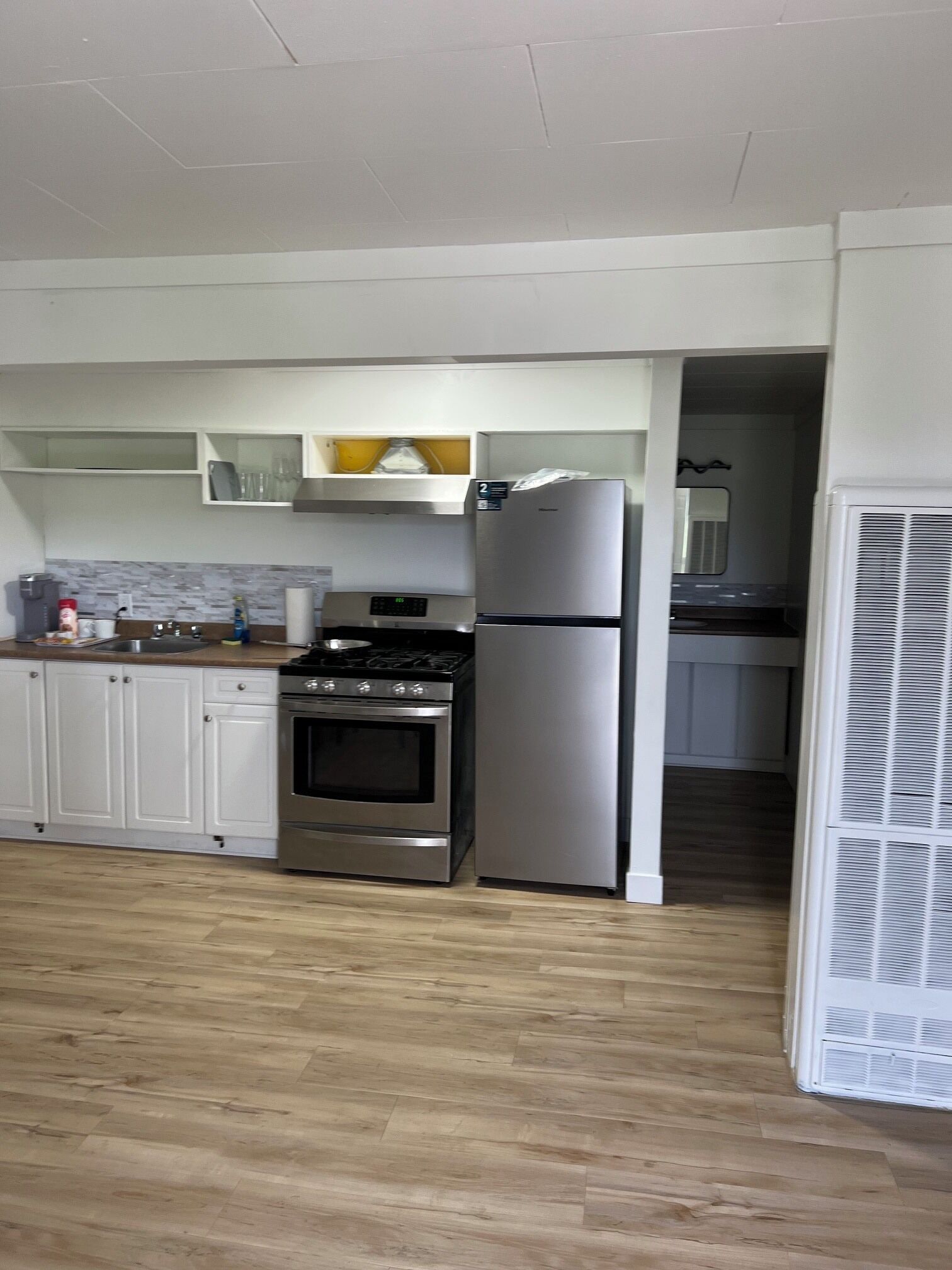 Una cocina con armarios blancos, un refrigerador de acero inoxidable, una estufa y un microondas.