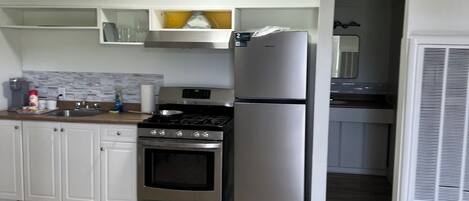 Una cocina con armarios blancos, un refrigerador de acero inoxidable, una estufa y un microondas.