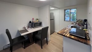 Una cocina compacta con una mesa de comedor, sillas, microondas, refrigerador y ventana con vistas.