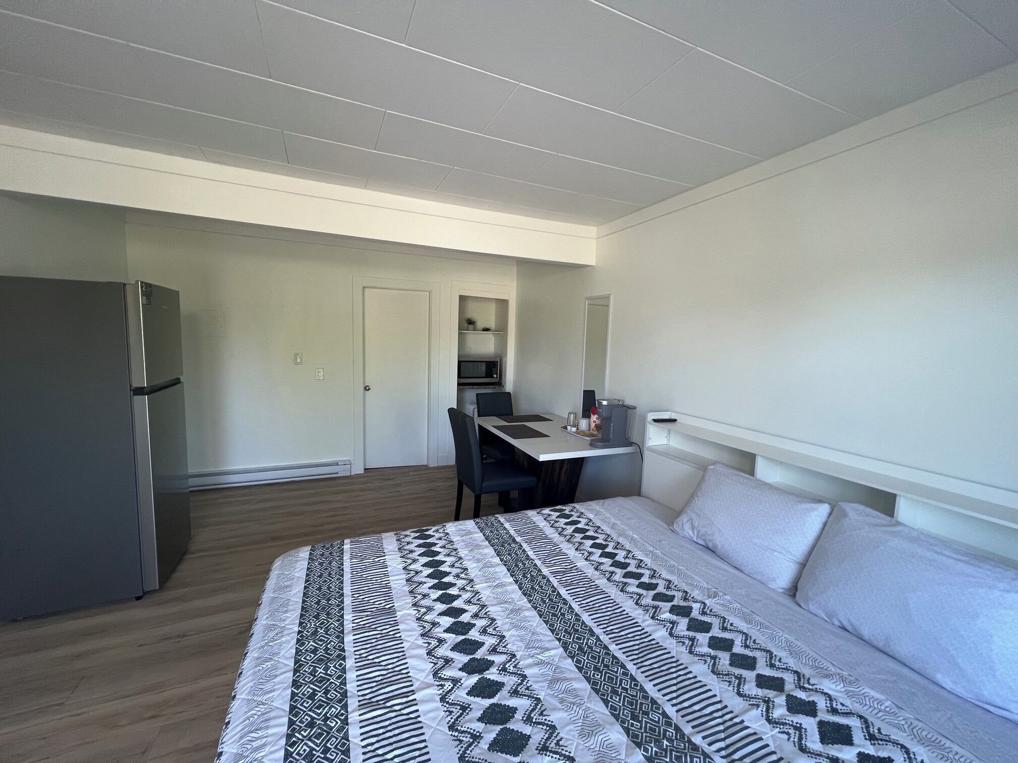 Una habitación de hotel con una cama, un escritorio, un microondas y un refrigerador.