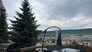 Un patio con mesa y sillas, una parrilla y vistas a un pueblo y montañas.