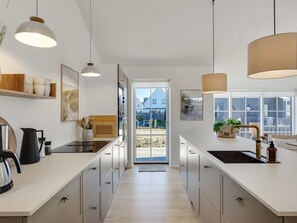 A modern kitchen with a large island, pendant lights, and a view to the outside. - "Raimund" - 600m from the sea by Interhome (Løkken)