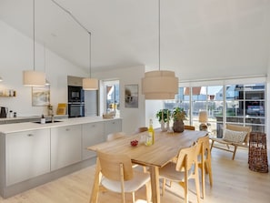 A modern kitchen with a central island, pendant lighting, and a view of the outside. - "Raimund" - 600m from the sea by Interhome (Løkken)