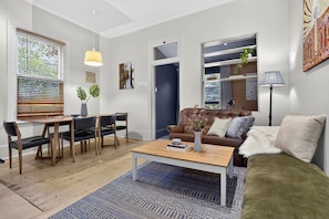 Ein modernes Wohnzimmer mit einem braunen Ledersofa, einem Holztisch und einem Essbereich mit Tisch und Stühlen.