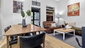 Ein modernes Wohnzimmer mit Esstisch, Ledersesseln, einem braunen Sofa, einem Couchtisch und Kunstwerken an den Wänden.