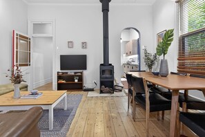Ein Wohnzimmer mit Kamin, Fernseher, Esstisch und einer Couch.