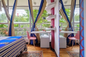 Ein Zimmer mit Bett, Schreibtisch und Stuhl, mit Blick auf Grünflächen.