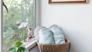 A room with a large window, a wicker basket with towels, a small vase with a plant, and a framed artwork on the wall. - Hostal Itzae Polanquito (Mexico City)