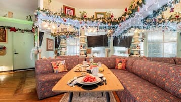 Una sala de estar acogedora con un sofá, una mesa de comedor con comida y decoración festiva.