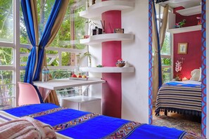 A bedroom with a bed, a desk, and a chair. There are shelves with decorative items and a window with curtains. - Hostal Itzae Polanquito (Mexico City)