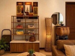 Ein Wohnzimmer mit einer Holzbibliothek, einer runden Stehlampe, einem Ledersofa und einem Spiegel.