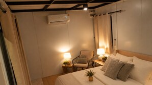 Une chambre à coucher comprenant un lit, deux tables de chevet avec des lampes, une chaise et un appareil de climatisation.