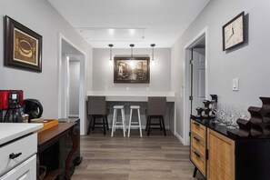 A modern kitchen with a dining area, a coffee machine, and a clock on the wall. - 3BR One Level Ranch home + Easy Hwy Access (Kansas City)