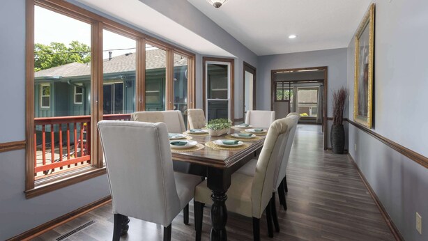 A dining room with a long table, chairs, and a view through large windows. - Sleeps8! Remodeled w/ Smart TVs , Near KC Stadium (Independence)
