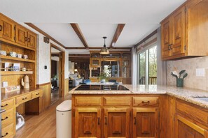 A kitchen with wooden cabinets, a granite countertop, and a central island. - 5 King Beds, Mins to Activities, & Kayaks (Kansas City)