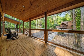 A wooden deck with a view of a cabin surrounded by trees. - Timber Vail | Luxury Cabin in the Woods (Sevierville)
