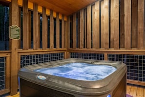 A hot tub with a wooden deck and a safety sign. - Timber Vail | Luxury Cabin in the Woods (Sevierville)