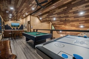 A pool table with a green felt surface, a pool cue, and a billiard ball rack. - Timber Vail | Luxury Cabin in the Woods (Sevierville)