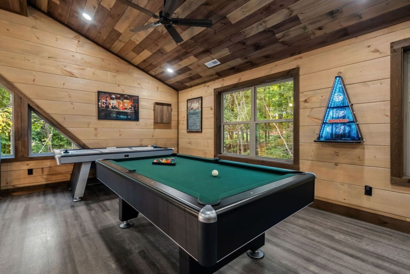 Een pooltafel in een ruimte met houten wanden en een schuin plafond.