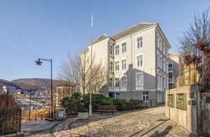 A multi-story building with a courtyard, a statue, and a bench. - Modern Apartment, Panoramic View in Heart of Bergen (Bergenhus)